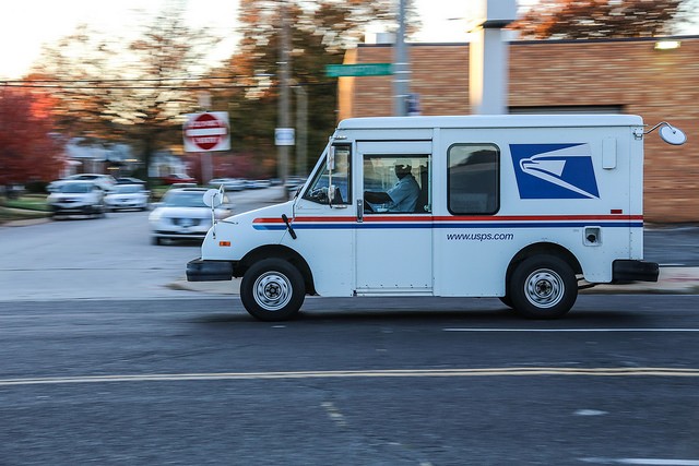 A mail truck drives down the street