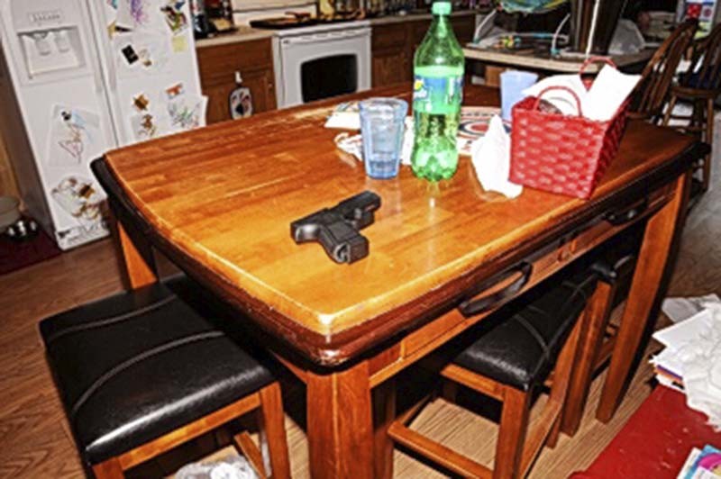 Lasley's gun, photographed as evidence on the family's kitchen table after the shooting. - COURTESY OF ST. LOUIS COUNTY POLICE