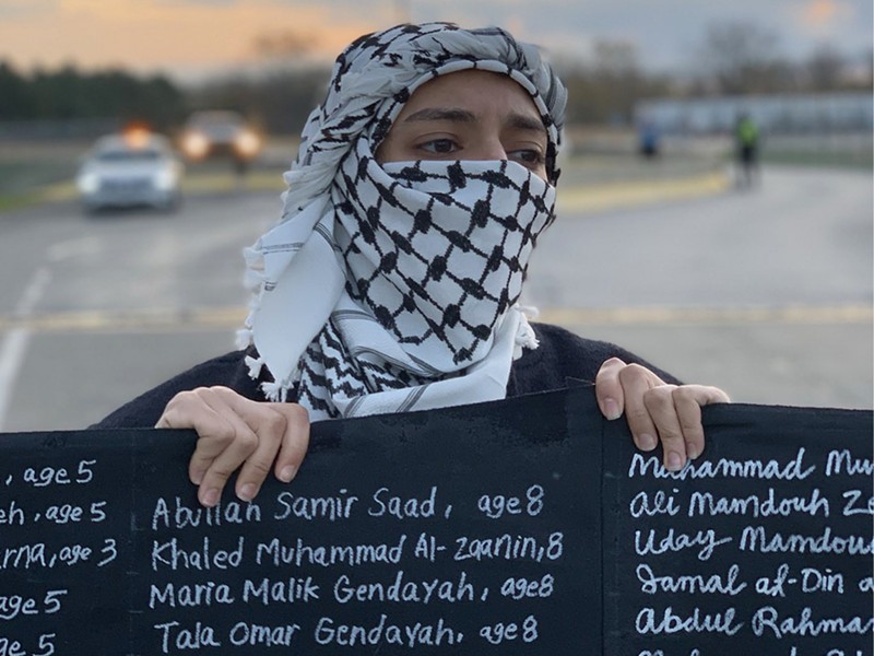 An activist holds a sign containing the names of slain Palestinian children outside of Boeing on Monday.
