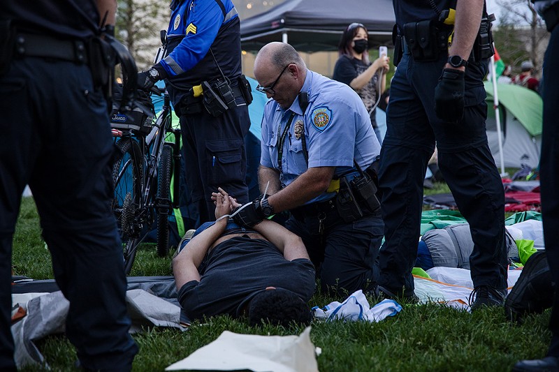 A police officer zip ties a protestor on the campus of Washington University on Saturday, April 27. - ZACHARY LINHARES