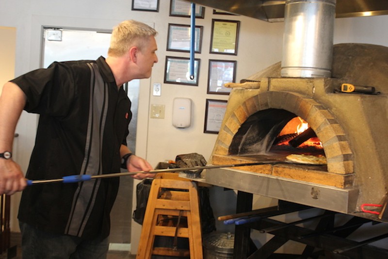 Ryan Reel works the pizza oven, which easily climbs to 800 degrees during a shift. - PHOTO BY SARAH FENSKE