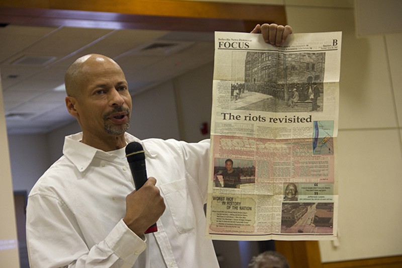Dhati Kennedy holds up a 1997 newspaper story on the commemoration of the 80th anniversary of the 1917 violence. - PHOTO BY DANNY WICENTOWSKI