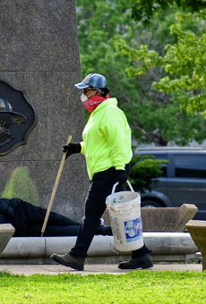 A worker picks up trash after the city removed two tent camps from downtown parks.