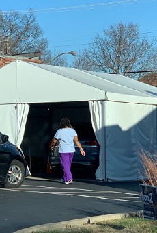 A health-care worker enters a COVID-19 testing tent.