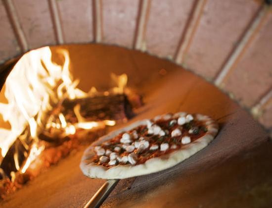 A pizza goes into the oven at Peel Wood Fired Pizza in Edwardsville. - JENNIFER SILVERBERG