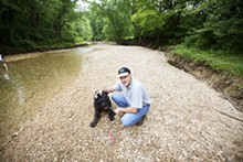 JENNIFER SILVERBERG - Steve Seyer and his giant schnauzer Dolphus on the gravel bed of Kiefer Creek in Castlewood State Park. Swimming in this water nearly killed the dog.