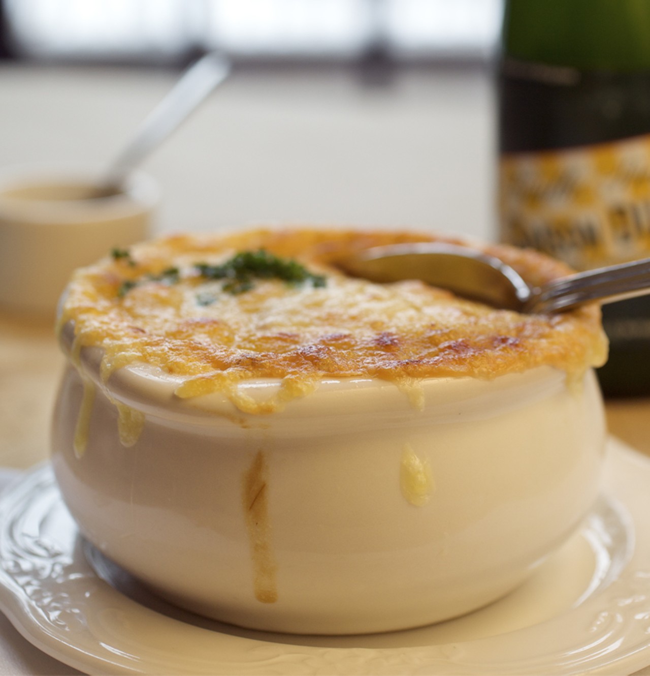 The onion soup, another one of the hors d&rsquo;oeuvres, is made with chicken stock, and is topped with a &ldquo;thick blanket of melted Gruy&egrave;re spilling over the edges of its crock.&rdquo; It is seen here with a Saison Dupont beer.