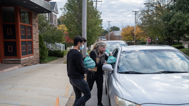 Volunteers deliver food to a car during a previous Drive-Thru Supper Club event.